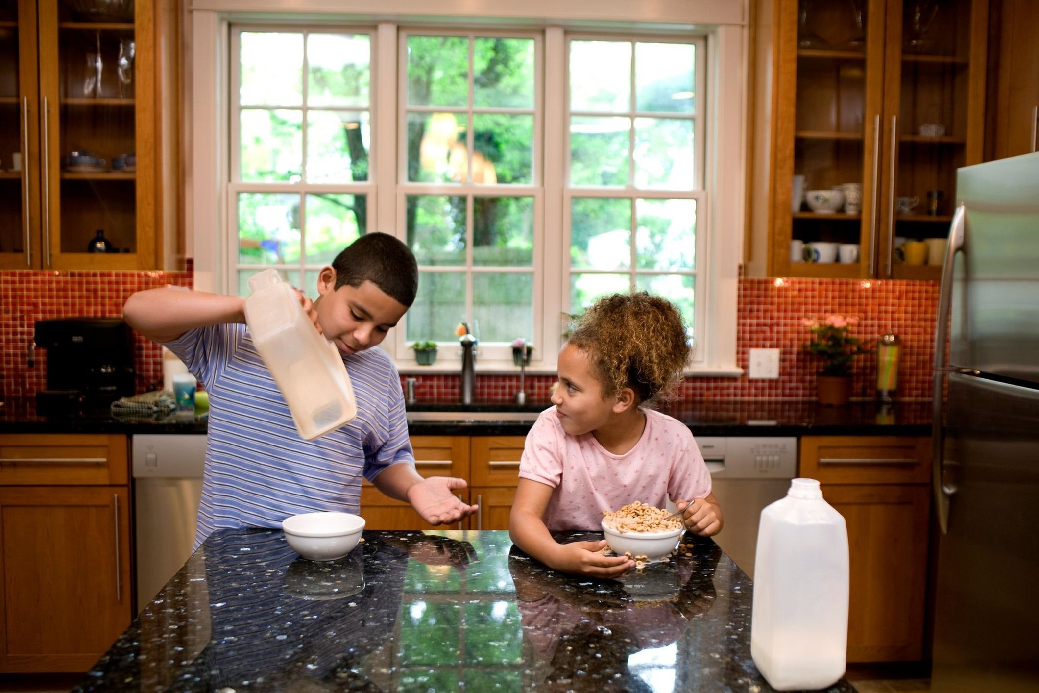 Girl looking at her brother after serving herself with all the cereal