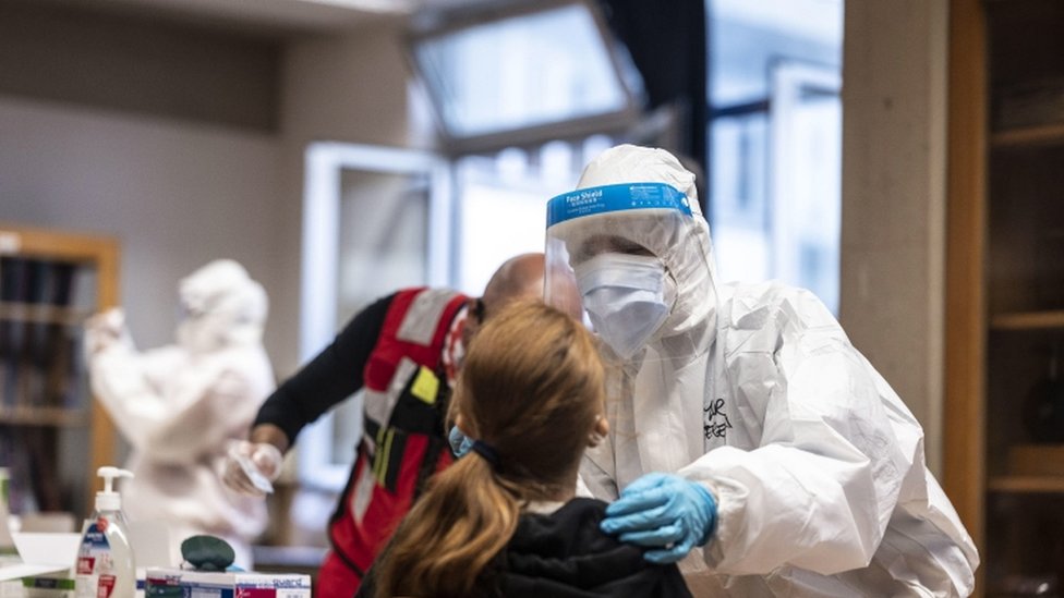 A health worker wearing overalls and a protective mask performs a swab test on a student in Florence, Italy