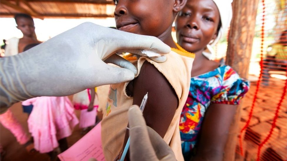 A young boy is injected while his mother watches