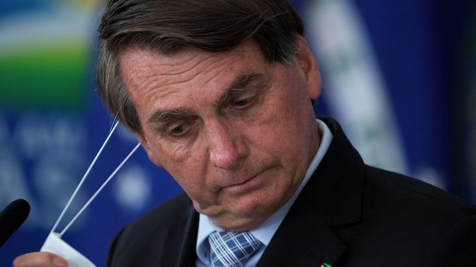 Brazilian President Jair Bolsonaro removes his mask during the signing ceremony of bills to expand the capacity to purchase vaccines by the Federal Government, at the Planalto Palace, in Brasilia, Brazil, 10 March 2020.