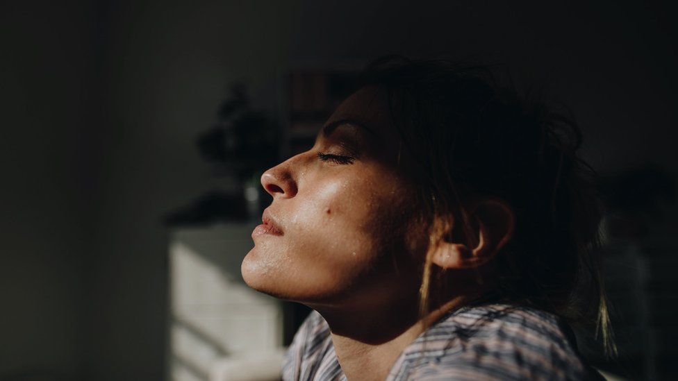 Woman, indoors, with the sun on her face