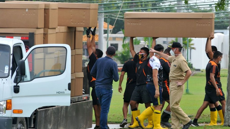 Soldiers in Ecuador pilling cardboard coffins on a lorry.