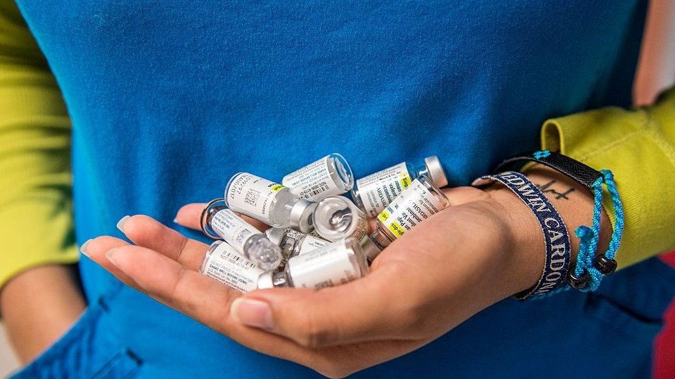 A nurse carries empty vials of HPV vaccine