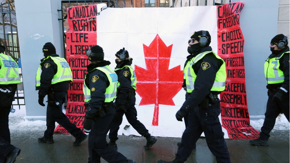 A group of police officers walk past a Canadian flag near Parliament Hill